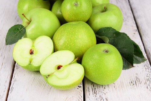 مجموعة من ثمار التفاح الأخضر، ومنها ما هو مقطوع بالنصف