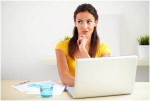 فتاة تجلس أمام اللابتوب وتفكر في حيرة