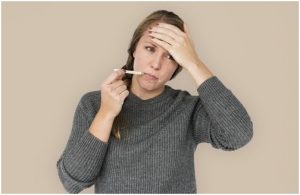 سيدة تشعر بالحمى وهي أحد مسببات خطوط الأظافر