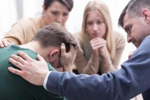 شاب يعاني من الإيذاء النفسي بينما من حوله يحاولون تهدئته