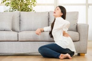 سيدة تجلس على الأرض وتتألم من جنبها