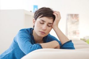 سيدة تضع يدها على رأسها وتغمض عينها من الإرهاق