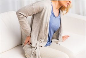 فتاة تضع يدها على جانبها الخلفي من الألم