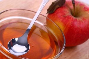 تفاحة ووعاء به كمية من خل التفاح