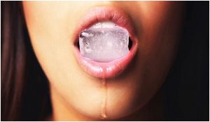 فتاة تمسك مكعب ثلج بأسنانها