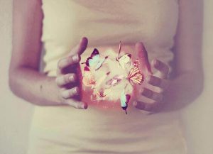 فتاة تحيط مجموعة من الفراشات بيديها