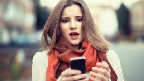 فتاة تقف في الشارع وتنظر بإستغراب إلى هاتفها المحمول