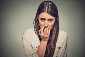 فتاة تقف وتعض أظافر يدها من القلق الشديد