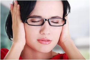 فتاة تغمض عينيها وتعاني من طنين الأذن