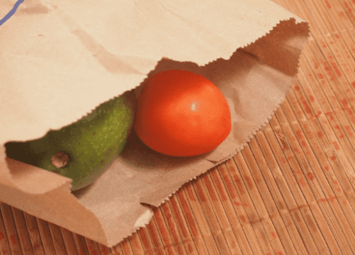 كيس ورقي يحتوي على أفوكادو وطماطم