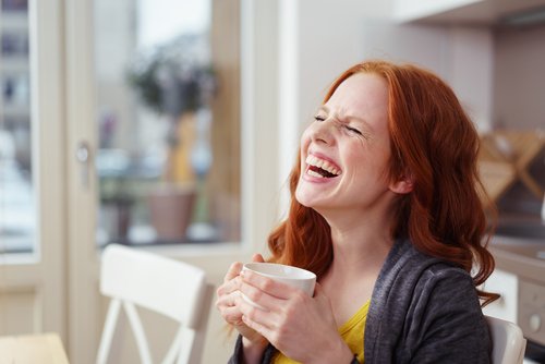 سيدة تضحك تشرب القهوة
