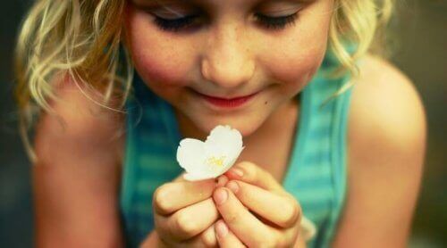 طفلة سعيدة تحمل زهرة بيضاء
