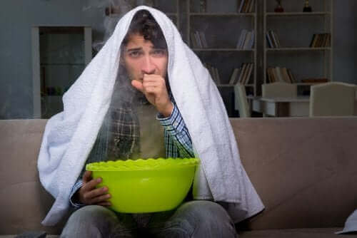 نزلات البرد - شخص يمسك بإناء وعلى رأسه منشفة