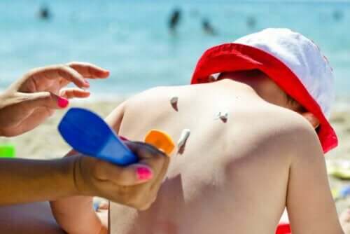 شخص يضع كريم واق من الشمس على طفل - آثار الإشعاع الشمسي