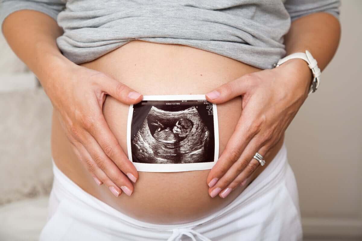 سيدة تضع صورة للأشعة السينية لرحمها وهي حامل أمام بطنها